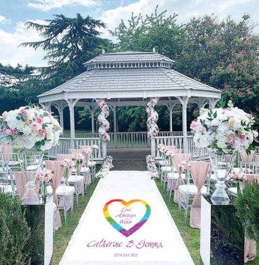 A beautiful wedding aisle runner with a Rainbow and the text "Love Always Wins" that can be personalised for LGBT weddings. . This is finished off with your own personalisation of the happy couples' names and the date of the wedding. The runner is printed on white canvas material. Width 36" (91.4cm).