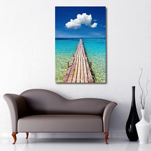 Load image into Gallery viewer, Portrait Art Canvas of long wooden pier heading out to turquoise blue sea with lone white cloud floating above in the centre of a blue sky
