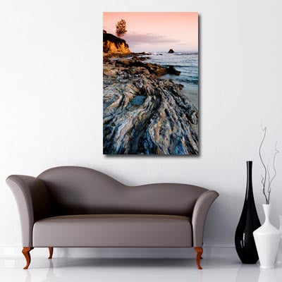 Portrait image of sunset over rock pools at sea with steep cliffs to the peripheral of the image