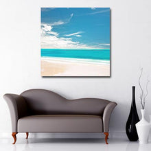 Load image into Gallery viewer, Square Canvas Art of white sand beach with clear turquoise sea and blue sky with intermittent clouds
